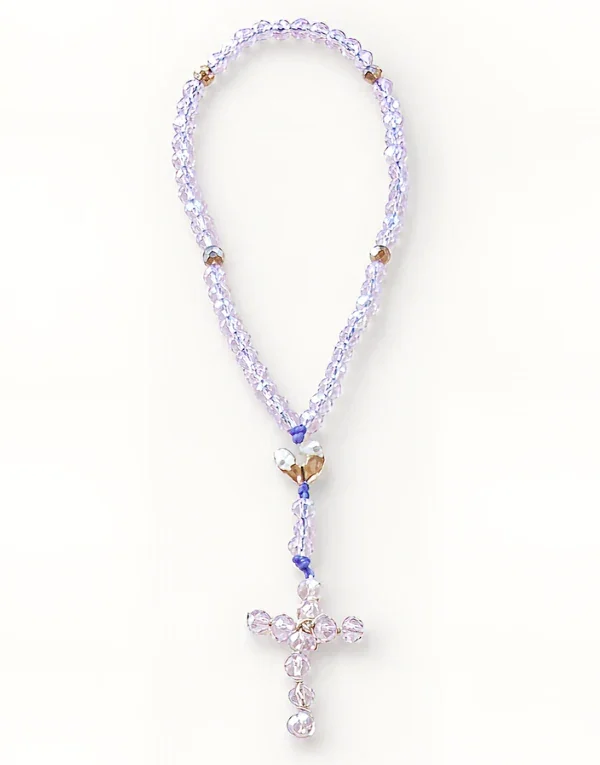 Rosario artesanal de cuentas lila y transparentes con crucifijo metálico y detalle de corazón dorado