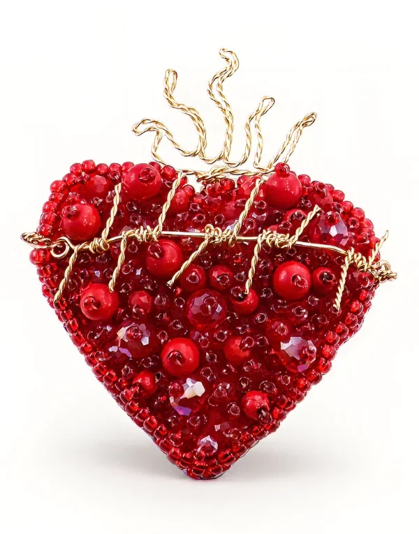 Corazón decorativo tejido con cuentas rojas y borde dorado sobre fondo blanco